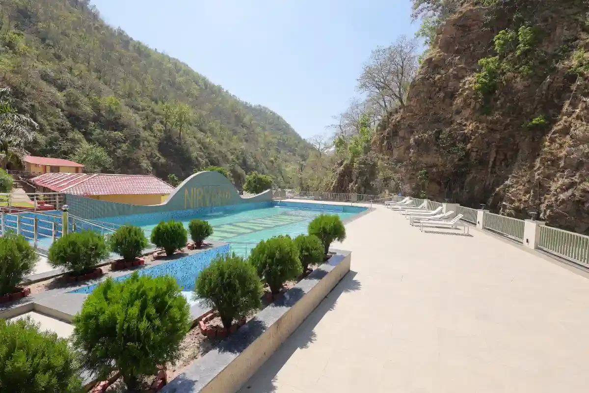 Nirvana River Resort’s swimming pool and sun terrace surrounded by wooded hills in Rishikesh